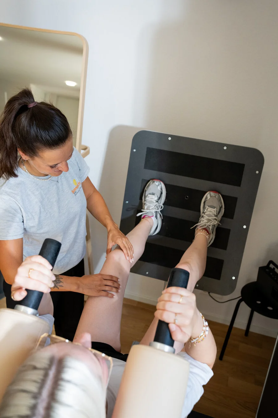 Patientin trainiert an der Beinpresse unter Anleitung der Physiotherapeutin