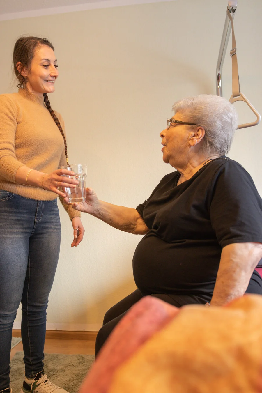 Mitarbeiterin und ältere Person sitzen gemeinsam am Tisch und unterhalten sich